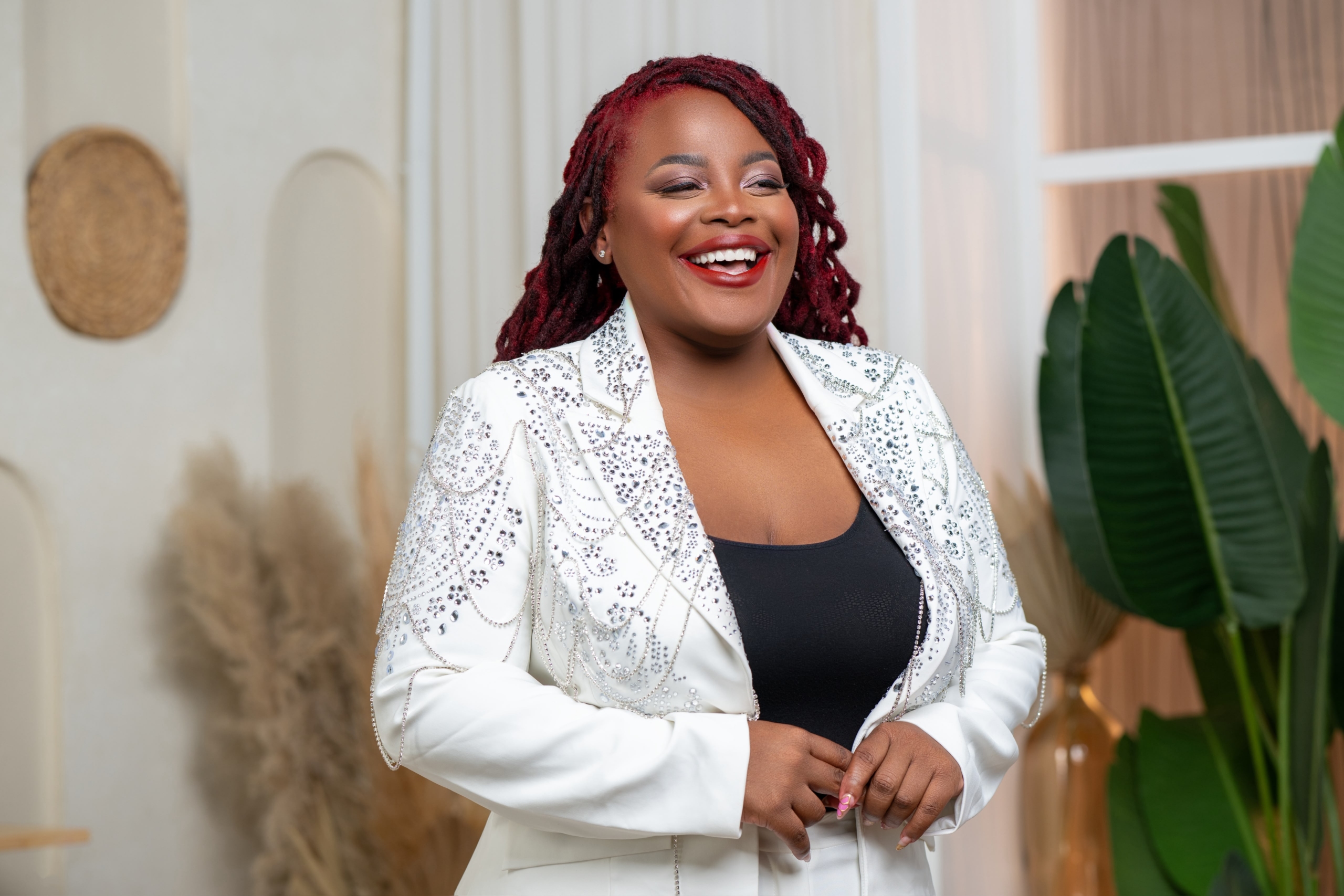 Ruthie Isabelle Jules, founder of Legacy Builder Insurance Agency, smiling in a white jeweled blazer