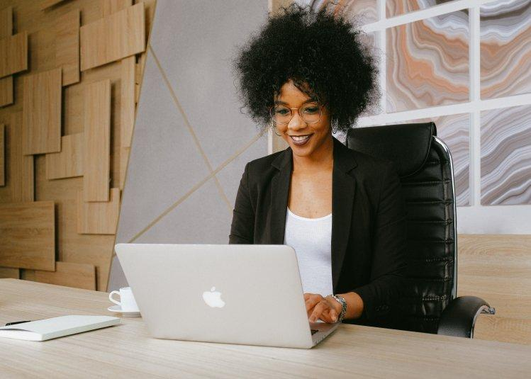 Woman in a black blazer working on a laptop
