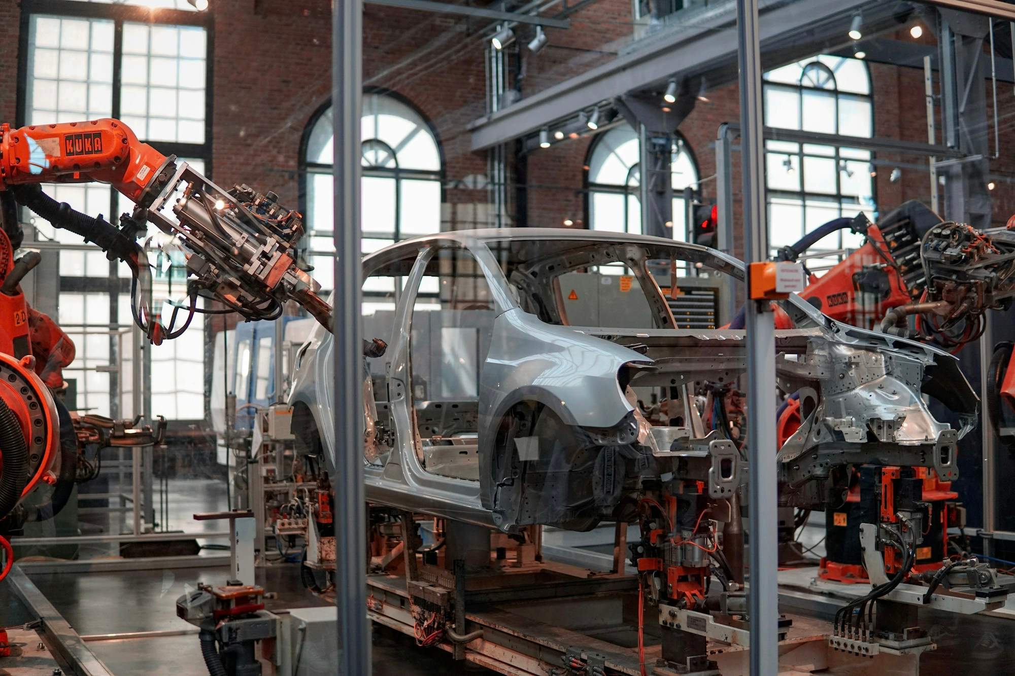 Robotic arms assembling a vehicle in an automated automotive factory